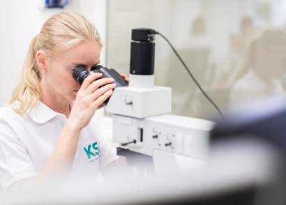 KSG-Mitarbeiterin untersucht eine Leiterplatte mit dem Mikroskop.