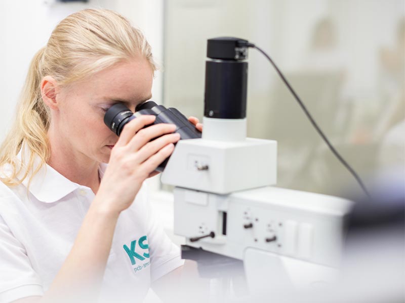 A woman looks through a microscope.